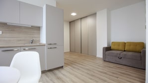Een moderne keuken met witte kasten, een houten aanrecht en een grijze bank met mosterdgele kussens.
