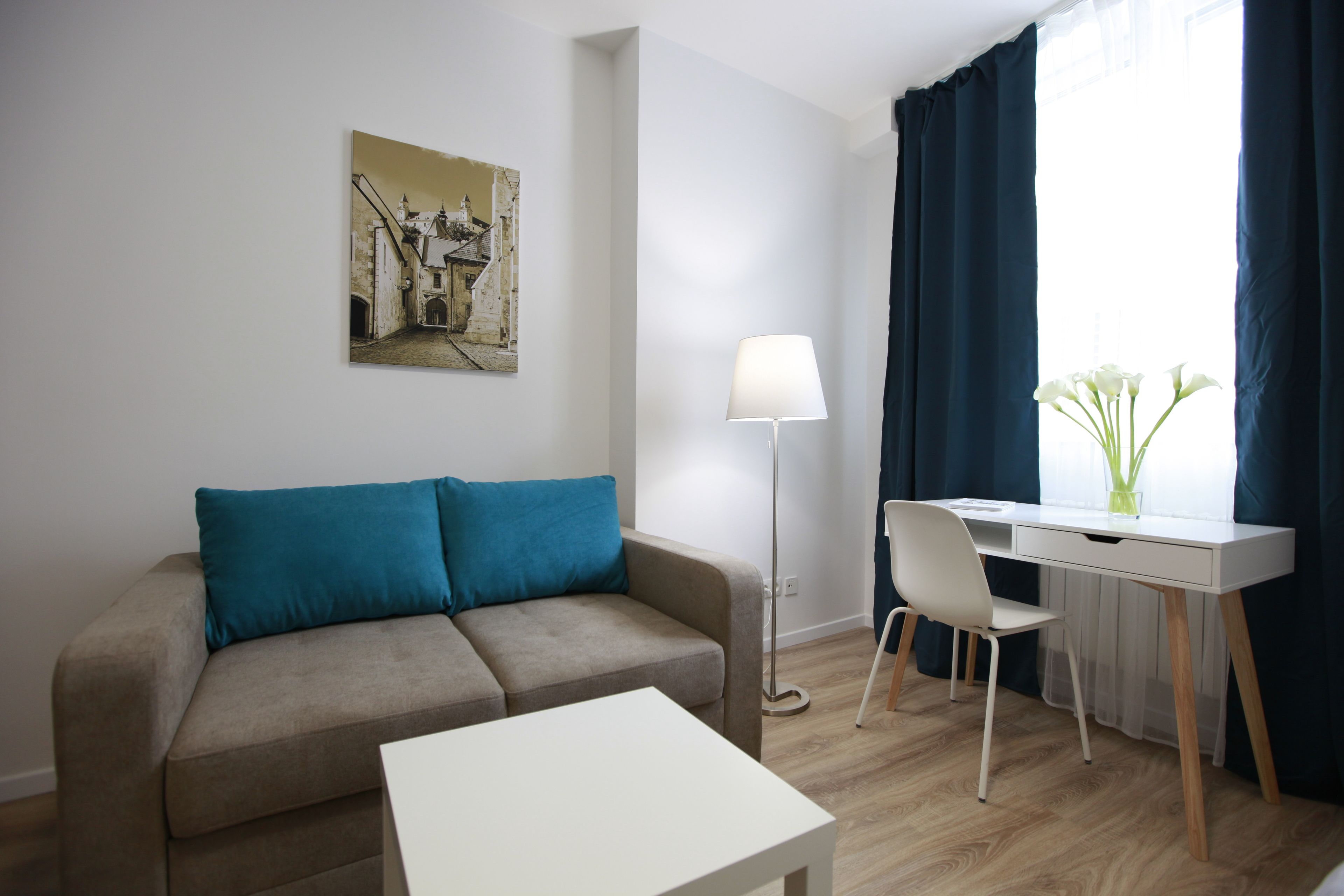 A modern living room with a sofa, a desk, and a lamp.