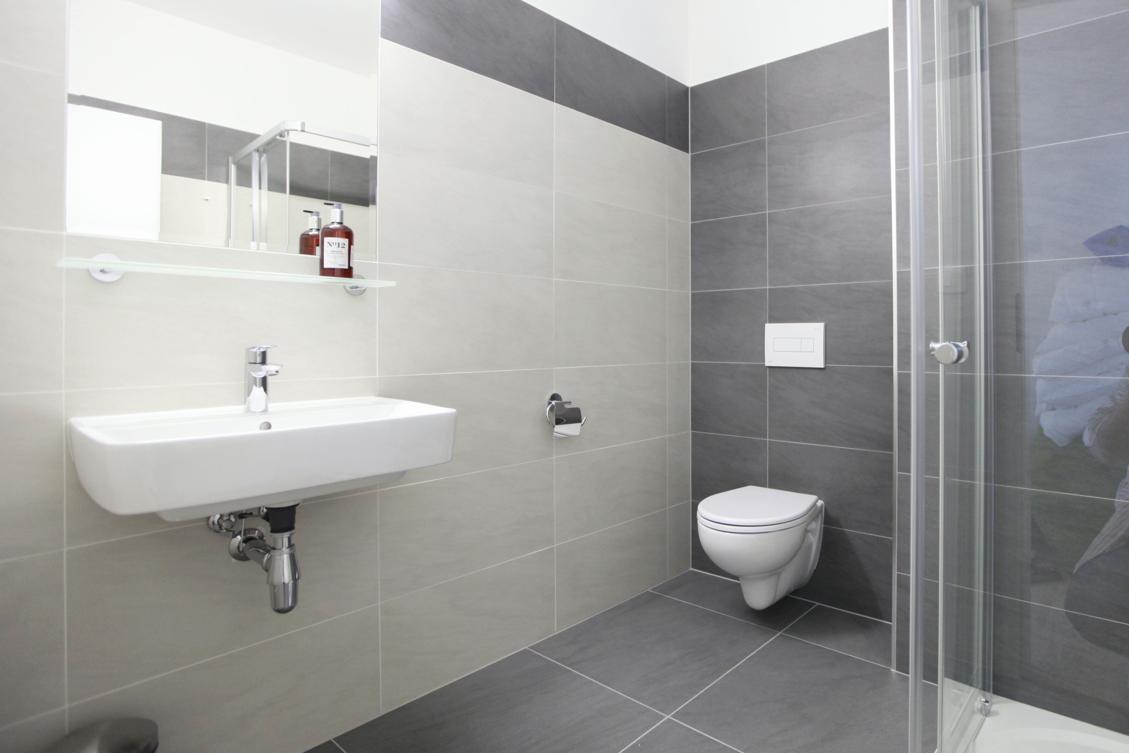 Une salle de bain moderne avec un lavabo blanc, des toilettes et une douche à parois de verre.