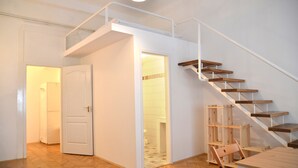 Un intérieur moderne avec un escalier en bois, un coin repas et une salle de bain à l’étage.