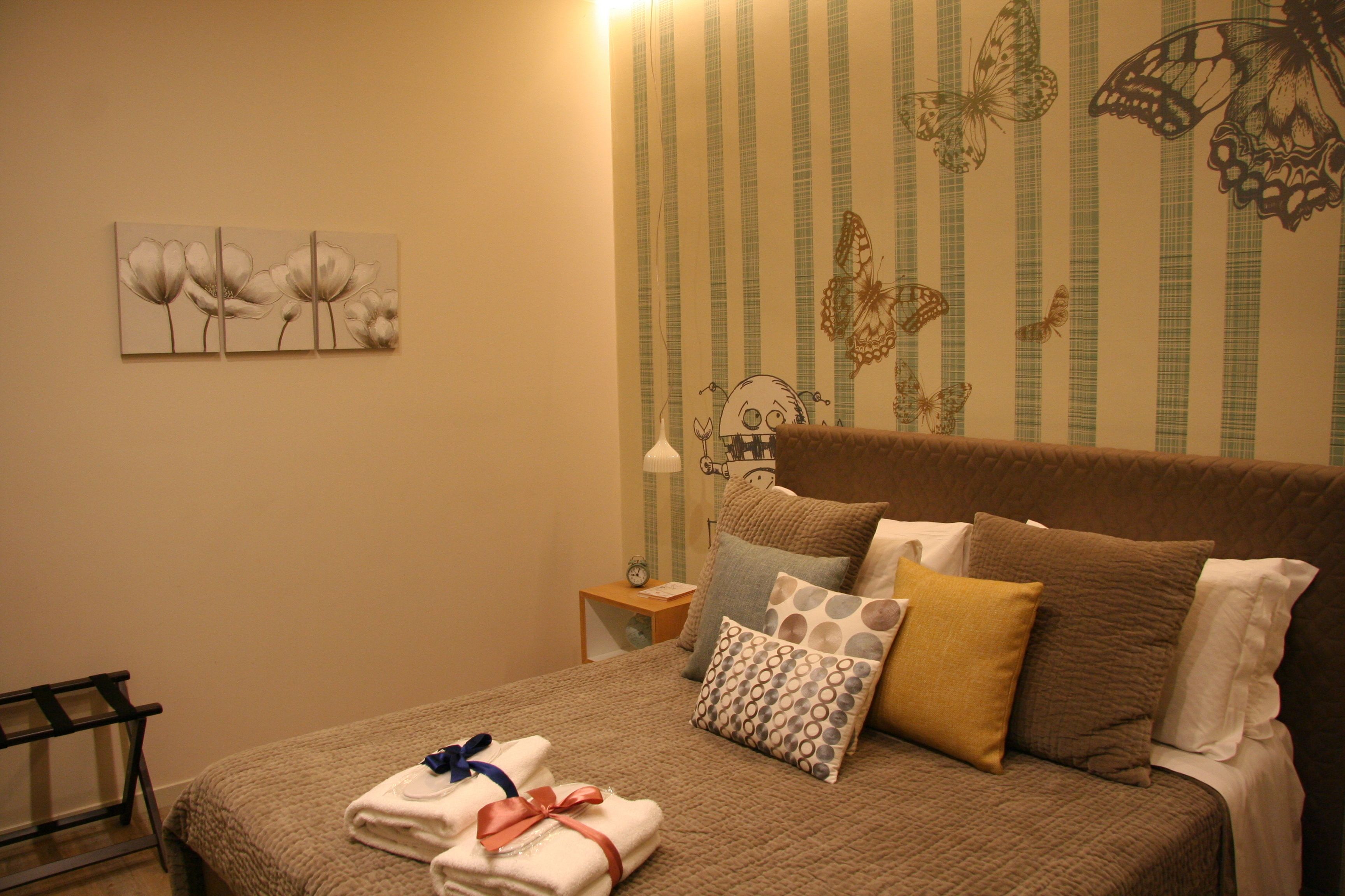A neatly made bed with a brown quilt, multiple pillows, and folded towels on the side.