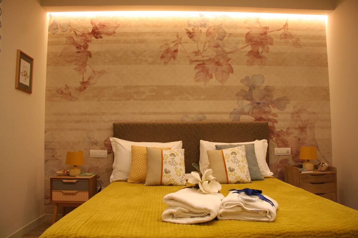 A hotel room with a bed, two nightstands, and a floral wallpaper.
