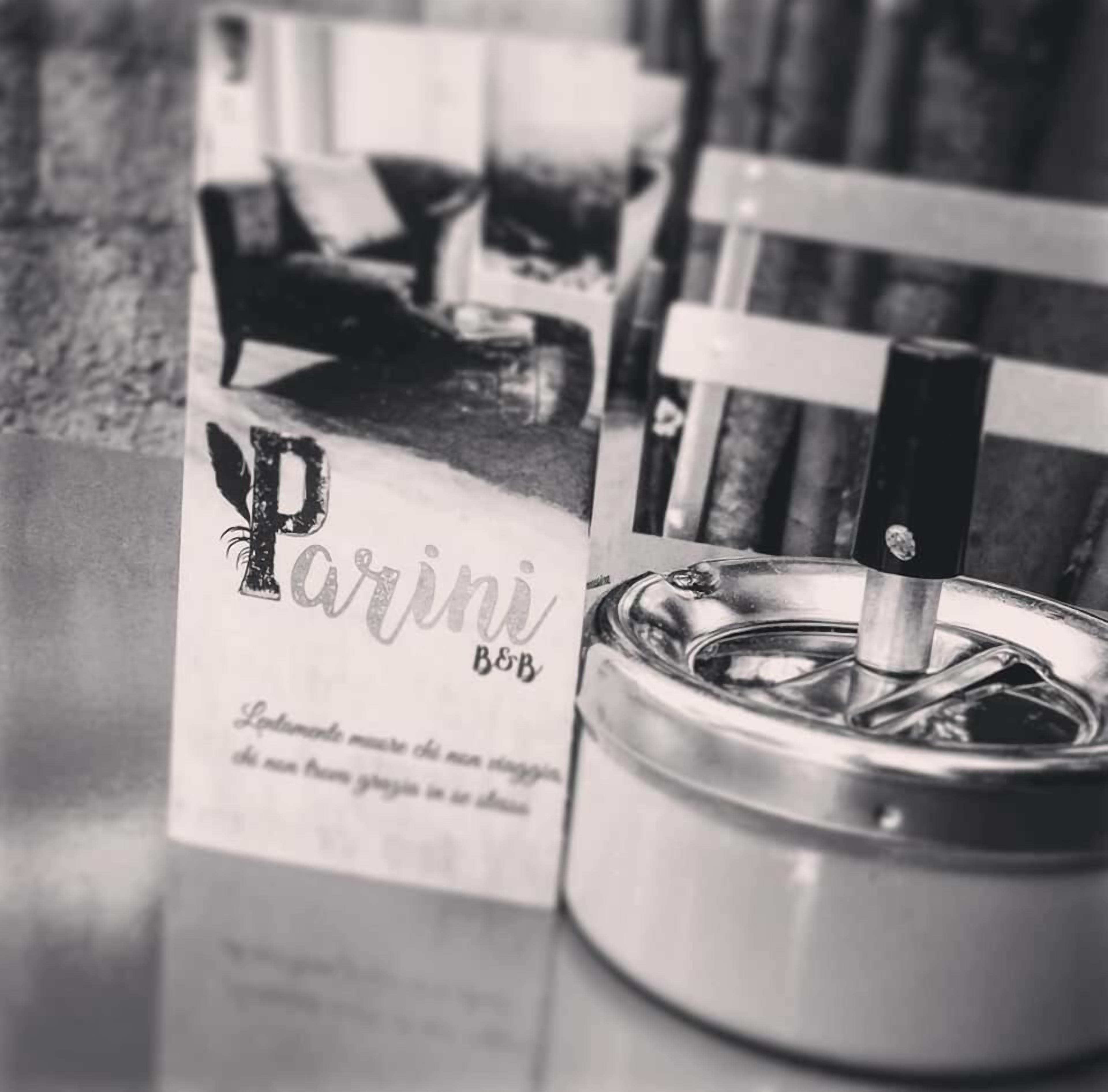 A metal container with a lid and a cigarette lighter, next to a sign with the text "Parini B&B".
