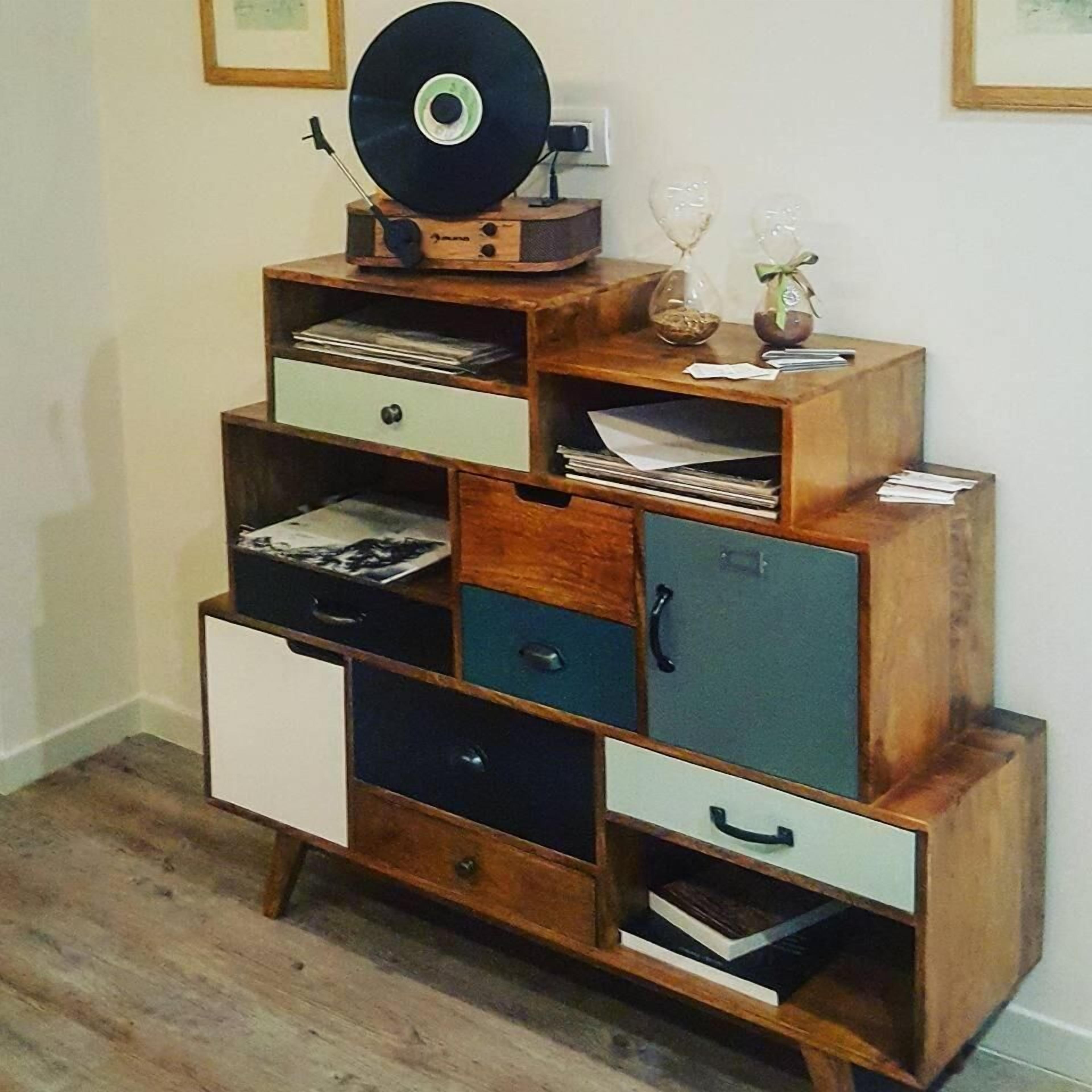Een houten kast met meerdere lades en planken, waarvan sommige papieren en een vinylplaat bevatten.