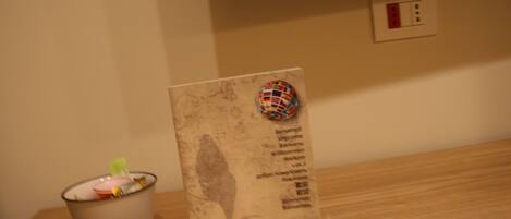 A welcome sign with multilingual greetings, a decorative globe, and a small trash bin on a wooden table.