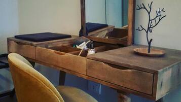 A wooden desk with a mirror, a small tree sculpture, and a chair.