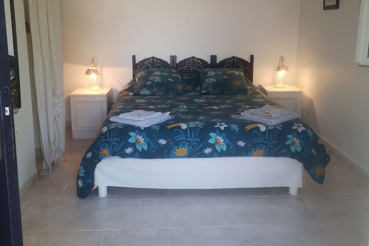 A bedroom with a bed, two bedside lamps, a nightstand, and a door.