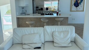 Ein modernes Wohnzimmer mit einem weißen Sofa und einer Küche im Hintergrund.