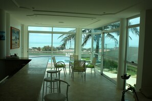 A spacious room with large windows offering a view of the ocean and palm trees.
