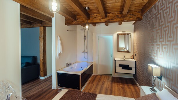 Un bany modern amb una banyera independent, un lavabo amb mirall i un sostre de fusta.