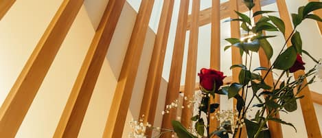 Una escalera de caracol de madera con una vista despejada de una rosa roja y flores de calcantita en un jarrón.