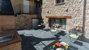 Edifici de pedra amb un pati que disposa de mobles d'exterior, un rentamans i una taula preparada per dinar.