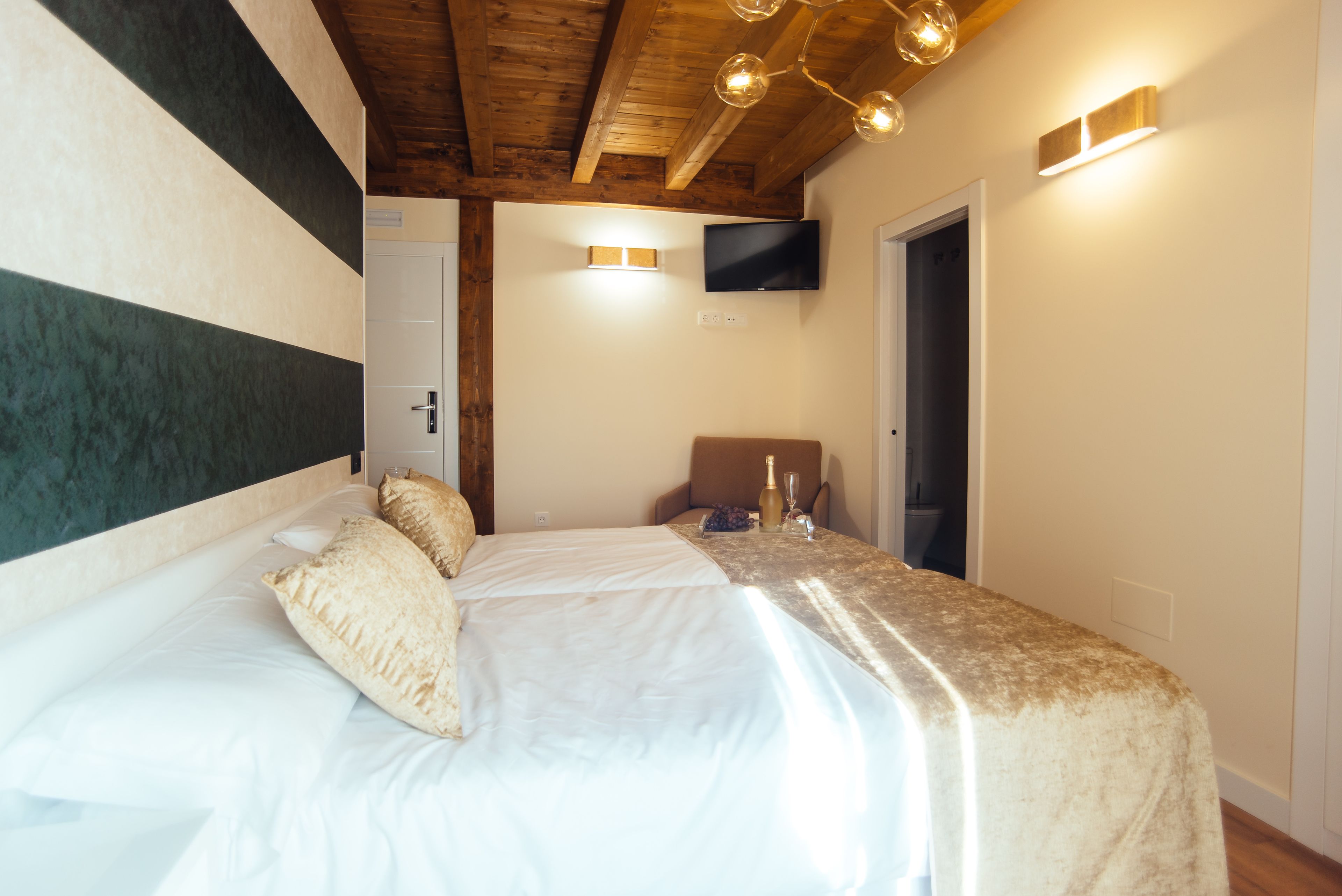 Un dormitorio con una cama grande, un televisor instalado en la pared y techo de madera.