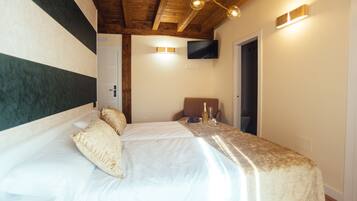 Un dormitorio con una cama grande, un televisor instalado en la pared y techo de madera.