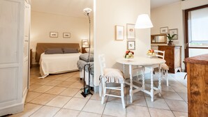 Une pièce bien éclairée, avec un lit, une table à manger et des chaises, ainsi qu’une lampe.