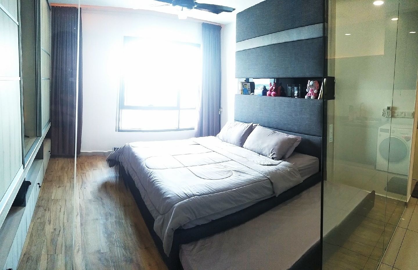 Un dormitorio moderno con una cama grande, un armario empotrado, una lavadora y un ventanal con cortinas.