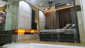 A modern bedroom with a glass partition, a bed, a desk, and a ceiling fan. - Summer 's Homestay (Seri Kembangan)