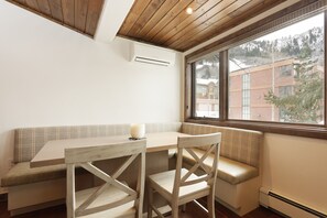 A cozy room with a wooden ceiling, a large window with a view of buildings, a bench, and a table with a cup. - Aspen Condo w/ Pool, Hot Tub & 2 Blocks to Gondola - FH4 by RedAwning (Aspen)