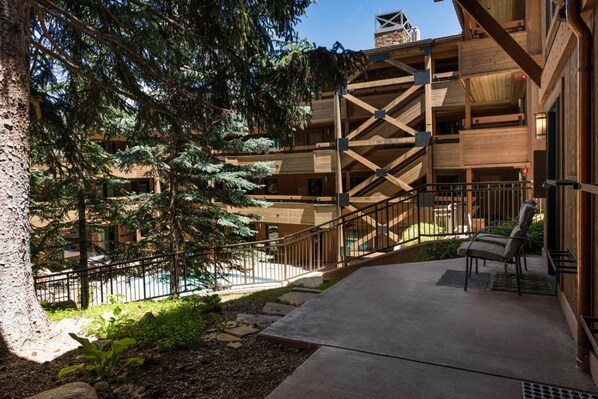 A multi-story building with a wooden exterior, outdoor seating area, and a staircase leading to the upper levels. - Aspen Condo w/ Pool, Hot Tub & 2 Blocks to Gondola - FH4 by RedAwning (Aspen)