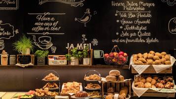 Un bufé de desayuno con diversos pasteles, frutas y una pizarra con citas motivacionales.