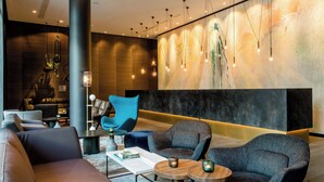 A modern lobby with a large abstract mural, comfortable seating, and ambient lighting. - Motel One Köln-Neumarkt (Cologne)