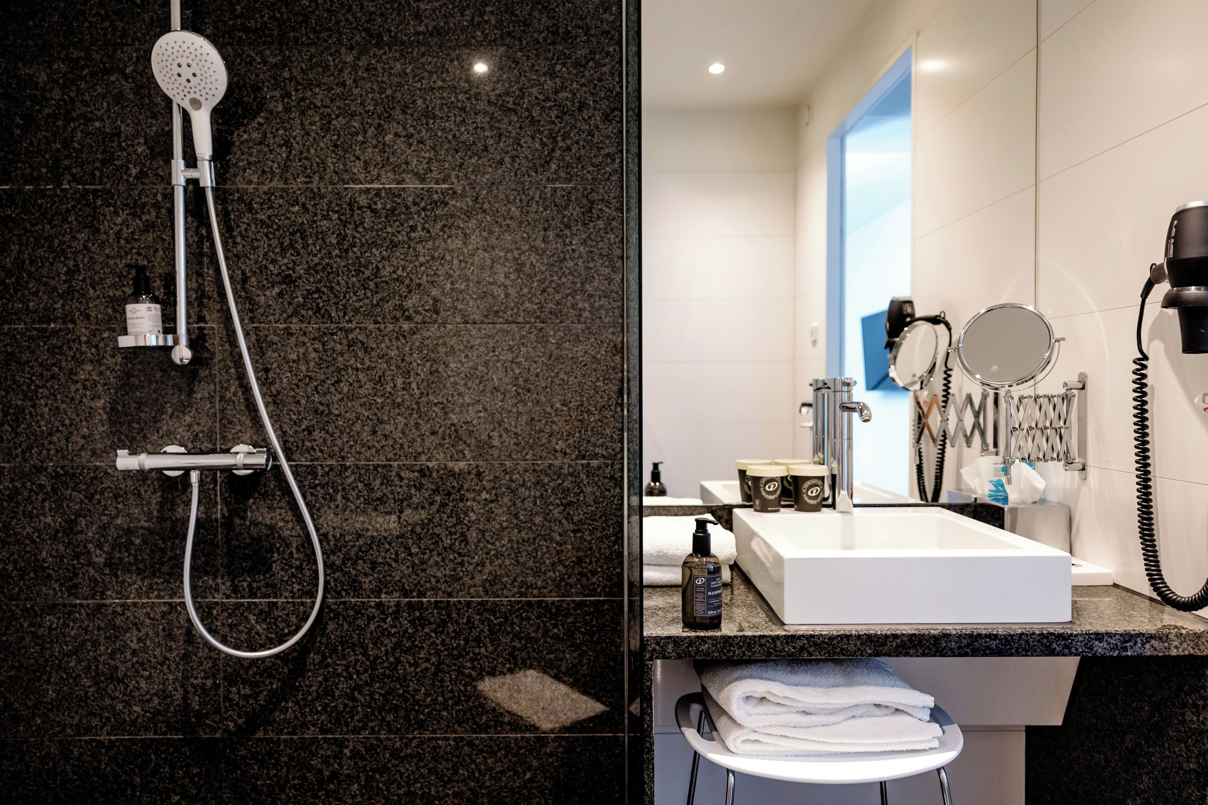 Un baño moderno con ducha, lavamanos y diversos artículos de aseo.