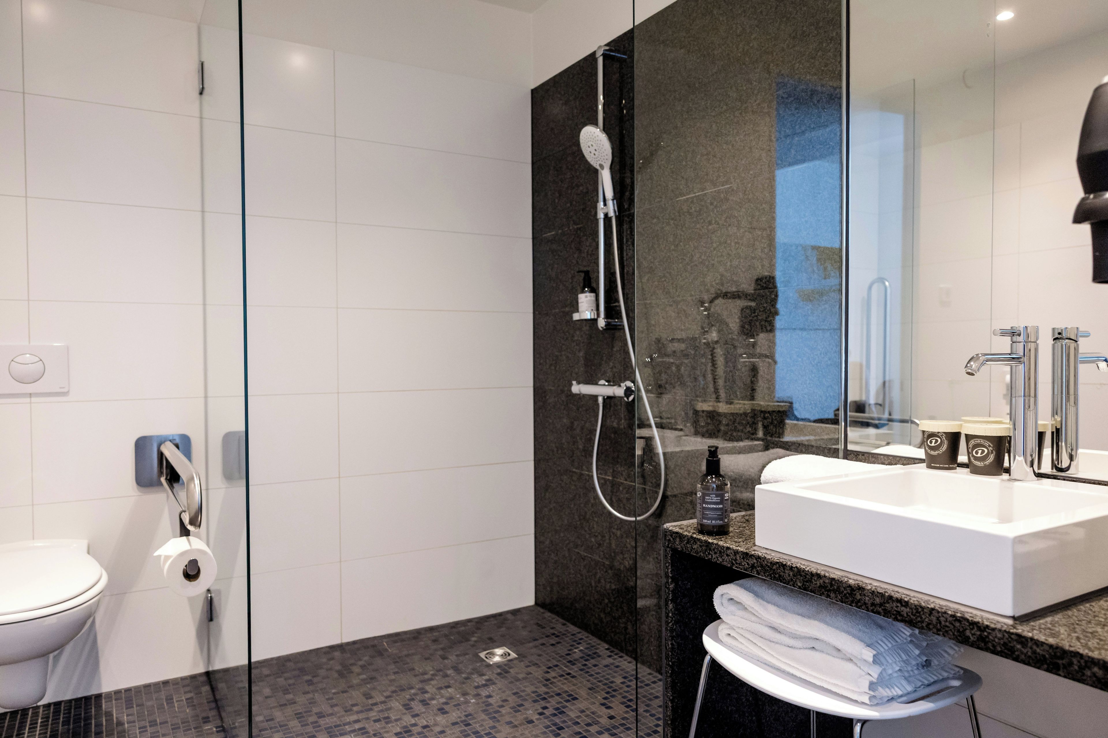 A modern bathroom with a glass shower enclosure, a white sink, and a marble countertop.