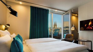 A hotel room with a large bed, a chair, a desk, and a TV. - Motel One Köln-Neumarkt (Cologne)