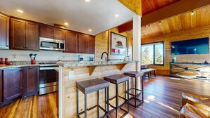 A modern kitchen with wooden cabinets, a stainless steel microwave, and a granite countertop. - Bridges Townhome 5 Large, Remodeled Mountain View Townhome with Private Jacuzzi, Steps to Eagle Lodge by RedAwning (Mammoth Lakes)