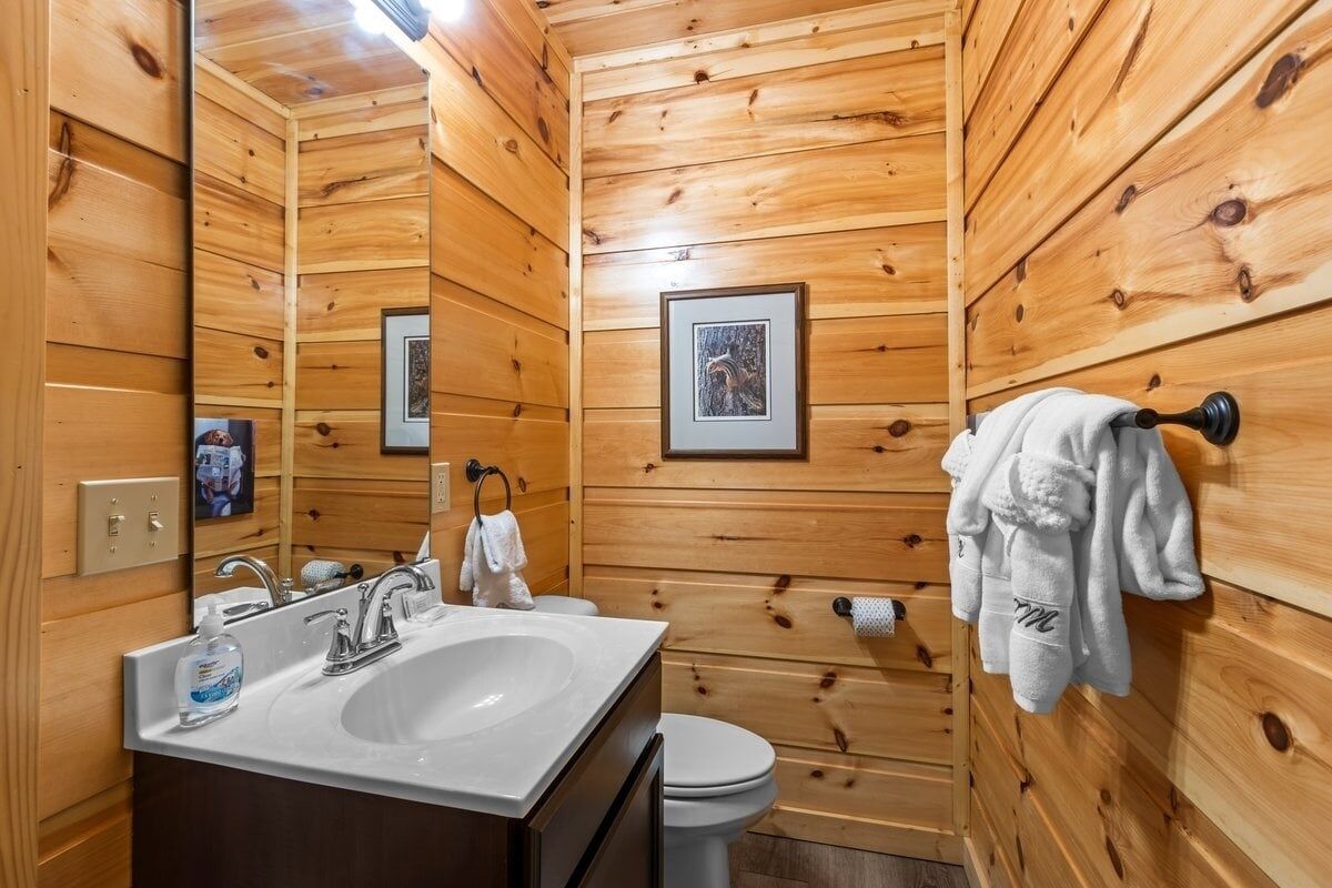 Une salle de bain aux murs lambrissés, équipée d  ’un lavabo, d’un miroir et de toilettes.