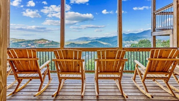 A wooden deck with four rocking chairs facing a scenic mountain view. - Mansion In The Sky 11 Bedroom Cabin by RedAwning (Gatlinburg)
