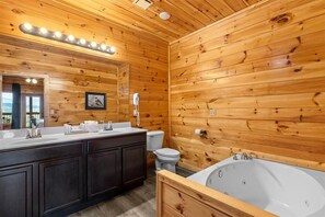 A wooden-paneled bathroom with a large vanity, a toilet, and a bathtub. - Mansion In The Sky 11 Bedroom Cabin by RedAwning (Gatlinburg)