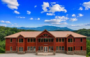 A large, two-story wooden building with a stone foundation, multiple windows, and a sign reading 'Focused Mission.' - Foxwood Mansion 14 Bedroom Cabin by RedAwning (Sevierville)