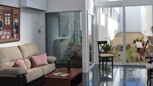 A modern living room with a sofa, coffee table, and a view of the outside through large windows. - Hotel La Alcoholera (Villaviciosa de Córdoba)