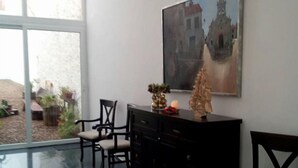 A room with a large window, a painting of a building, a cabinet, and two chairs. - Hotel La Alcoholera (Villaviciosa de Córdoba)