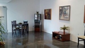 A spacious living area with a polished concrete floor, a dining table with chairs, a small cabinet with a plant, and artwork on the walls. - Hotel La Alcoholera (Villaviciosa de Córdoba)
