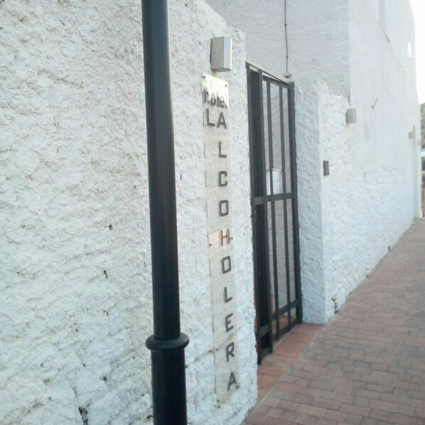 Un edificio blanco con un letrero que dice "Hotel La Colera" en una pared con textura.