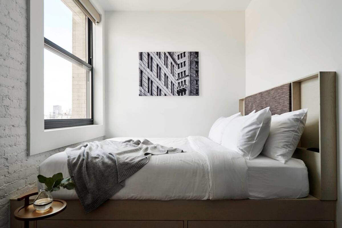 A bedroom with a bed, a window, and a wall-mounted picture.