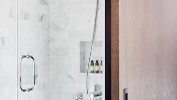 A modern shower with a handheld showerhead and a wall-mounted faucet.