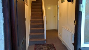 A staircase leading to a door, a radiator, and a hanging coat rack. - Le Buffle Noir Londres (London)