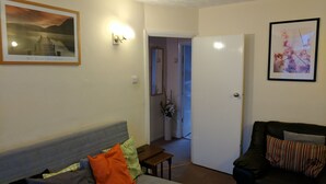 A living room with a grey sofa, a black armchair, and a small table. There is a white door leading to another room. - Le Buffle Noir Londres (London)