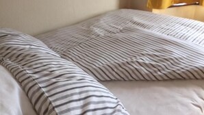 A bed with striped bedding and a plain wall. - Le Buffle Noir Londres (London)