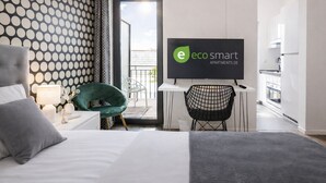 Et moderne hotelværelse med en seng, et skrivebord med et fjernsyn, en grøn stol og udsigt ud.