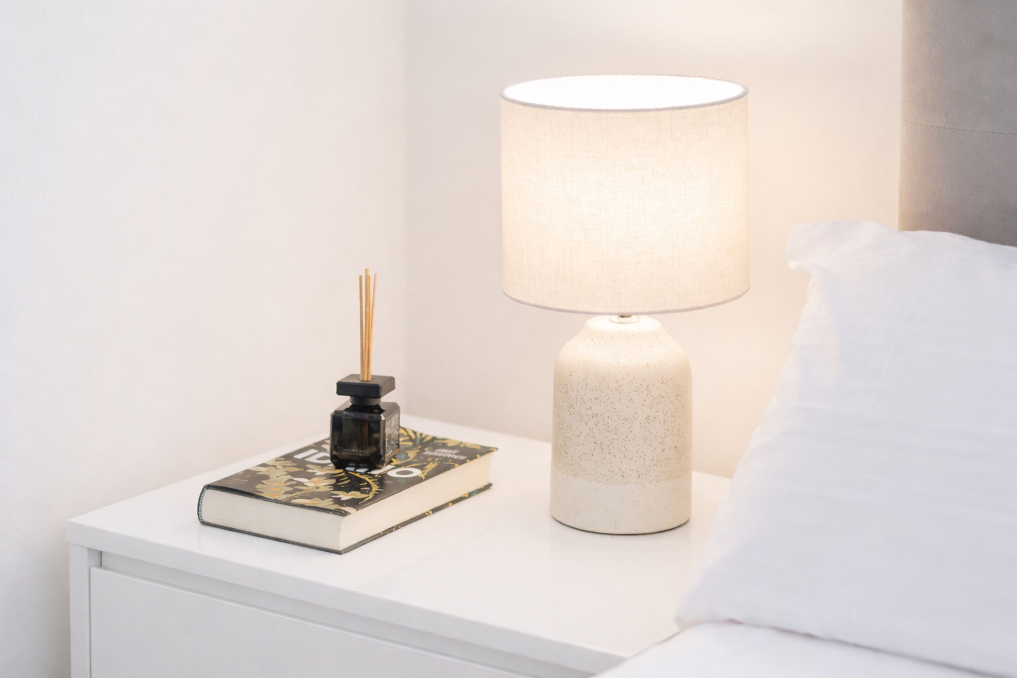 Ein Nachttisch mit Lampe, Buch und Dekoration.