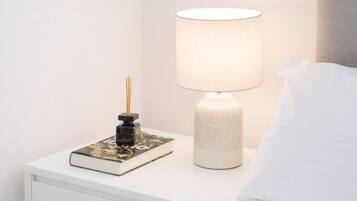 A bedside table with a lamp, a book, and a decorative item.