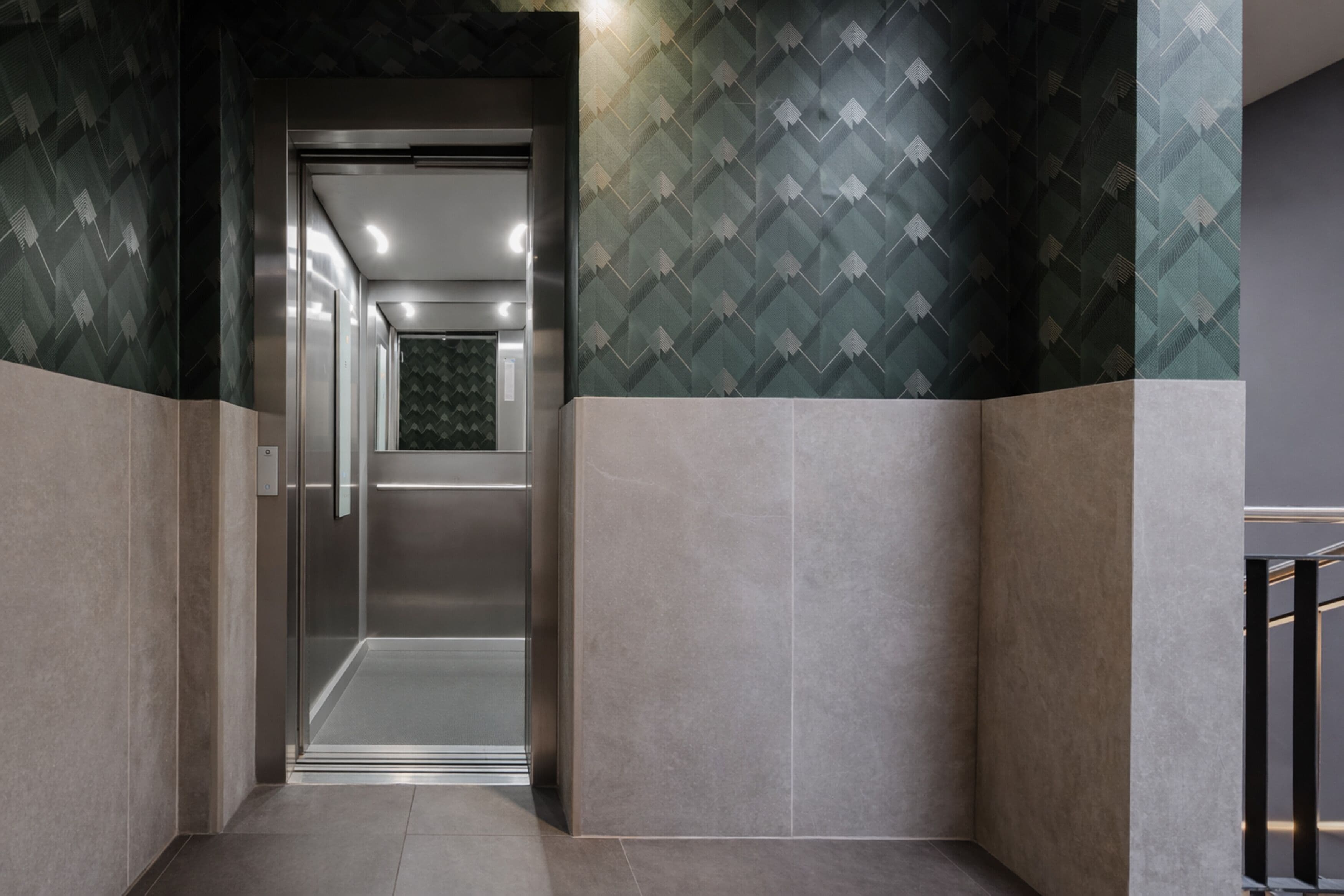 Um elevador moderno com parede de padrão geométrico e interior metálico.