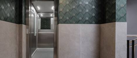 Um elevador moderno com parede de padrão geométrico e interior metálico.