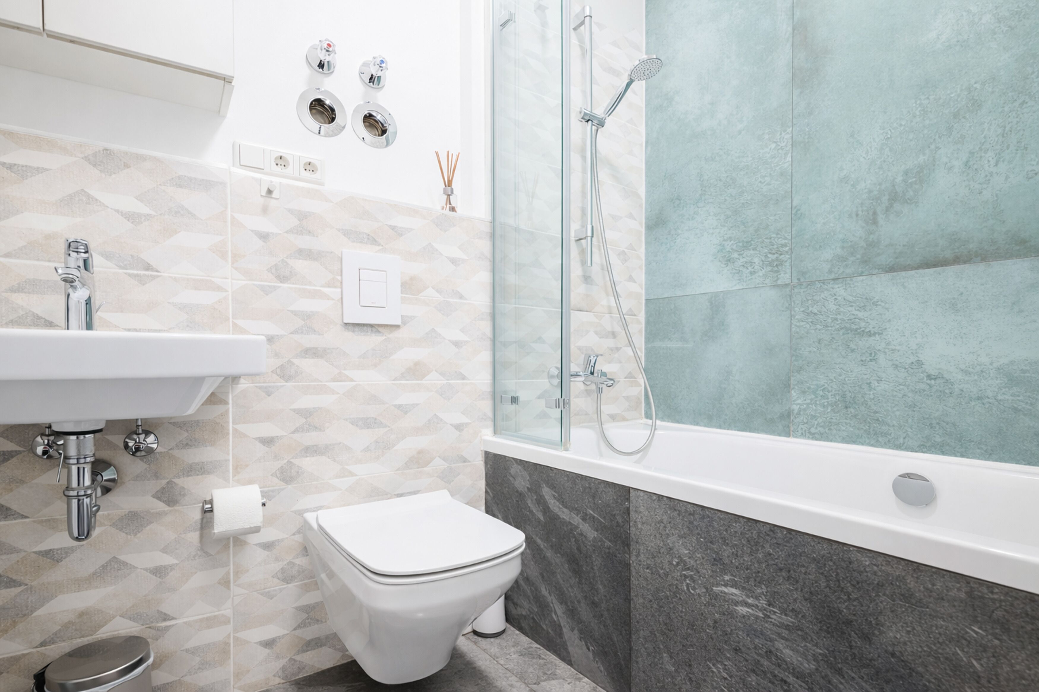 Une salle de bain moderne avec une douche à parois de verre, un lavabo blanc et des toilettes.