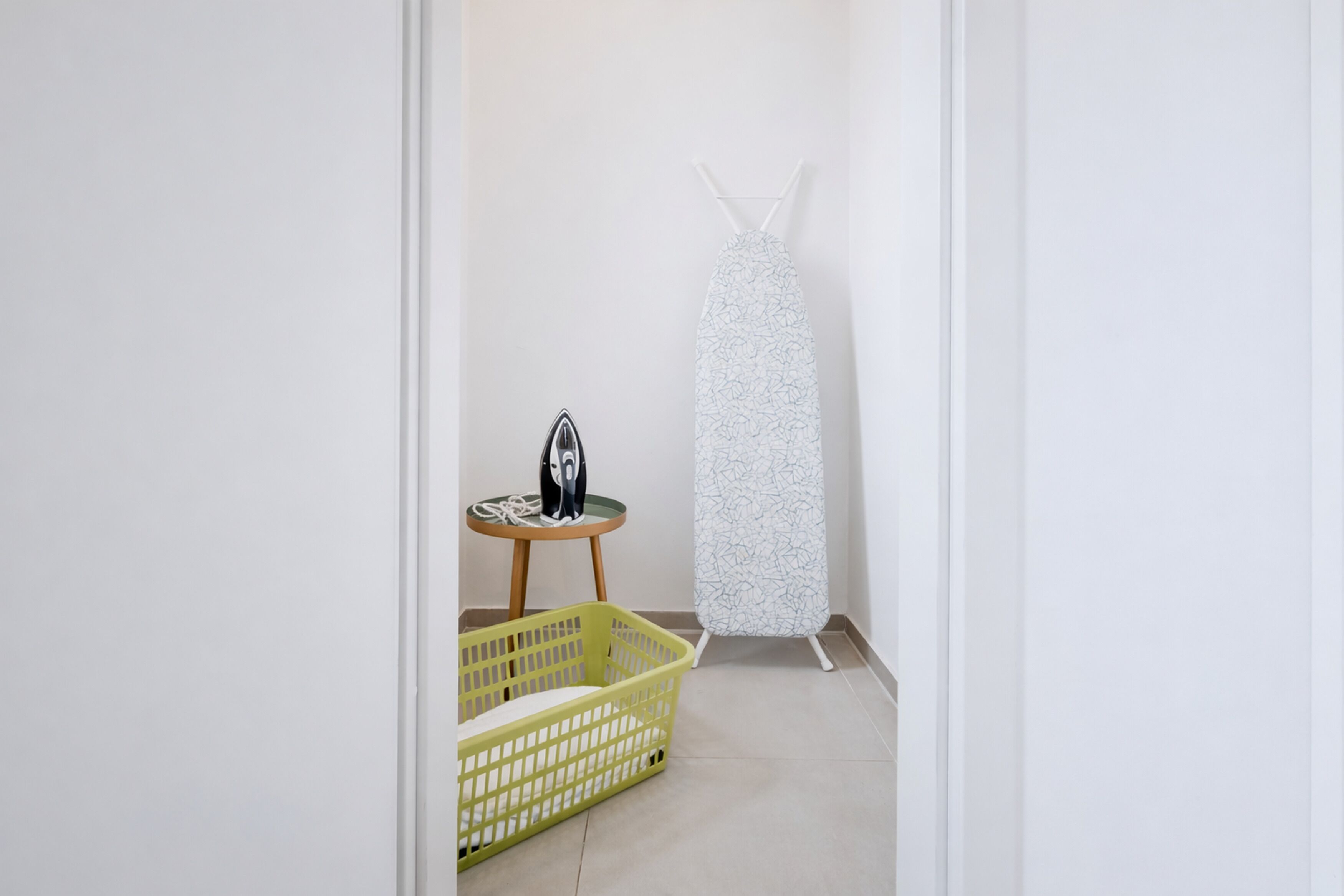 A laundry area with a hanging iron, a basket, and an ironing board.