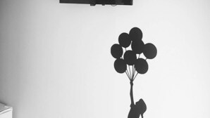 A room with a flat-screen TV mounted on the wall, a wall decal of a girl holding balloons, and a cat silhouette.